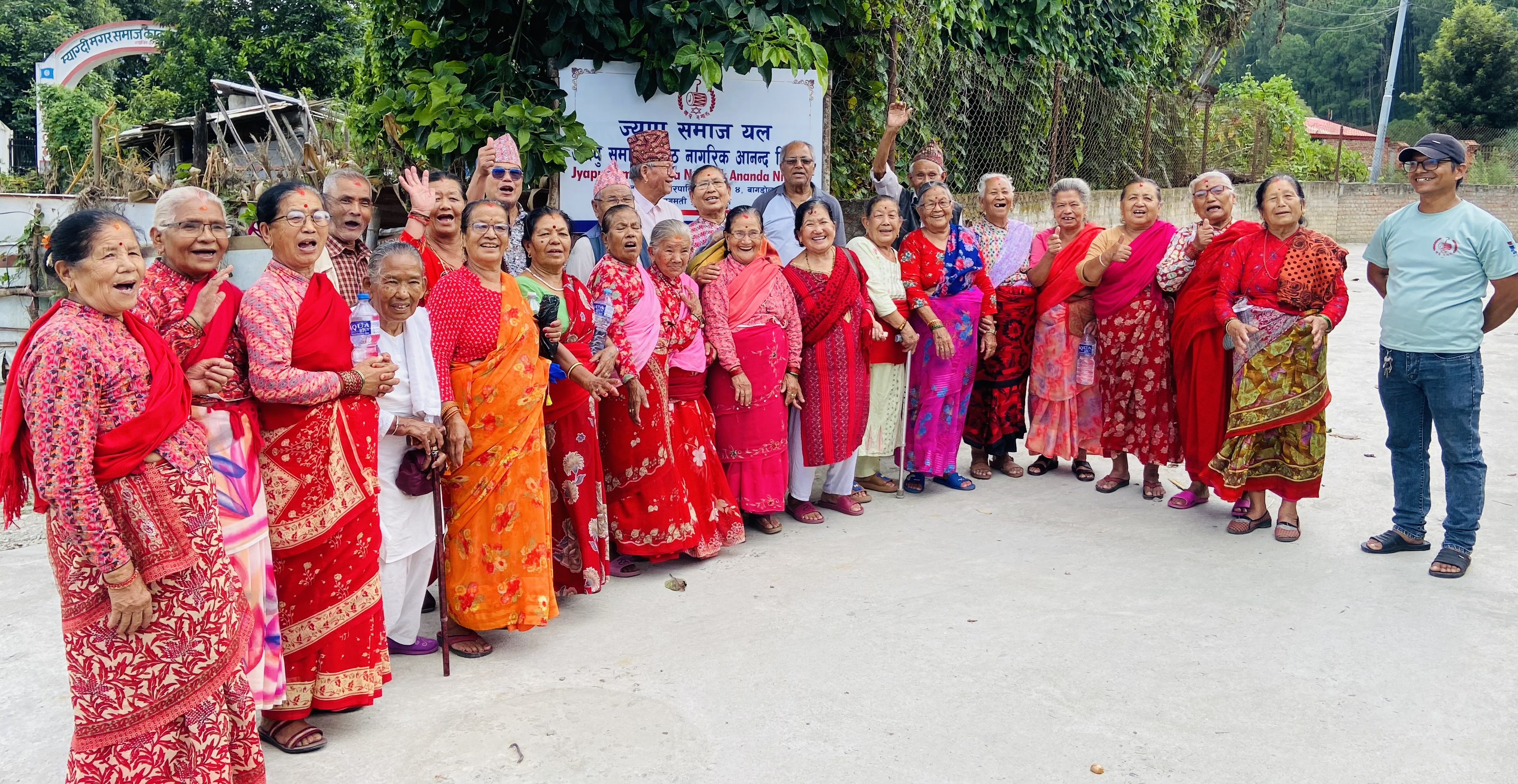 Group of smiling seniors and a volunteer outdoors at Ananda Niketan